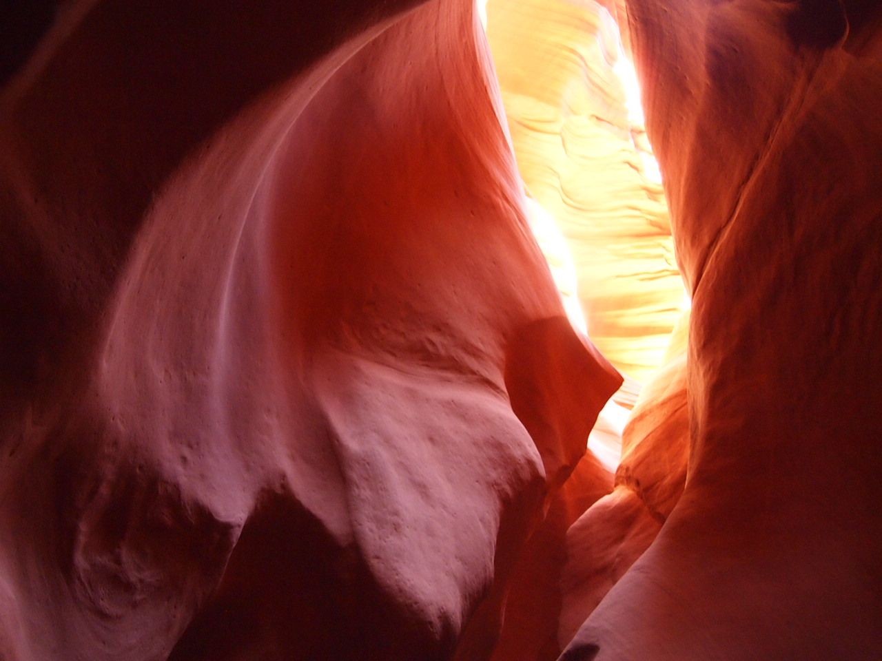 Sunlight illuminating the smooth, red rock walls of a narrow slot canyon.